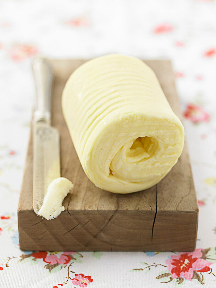 Homemade butter formed into a roll on a wooden board