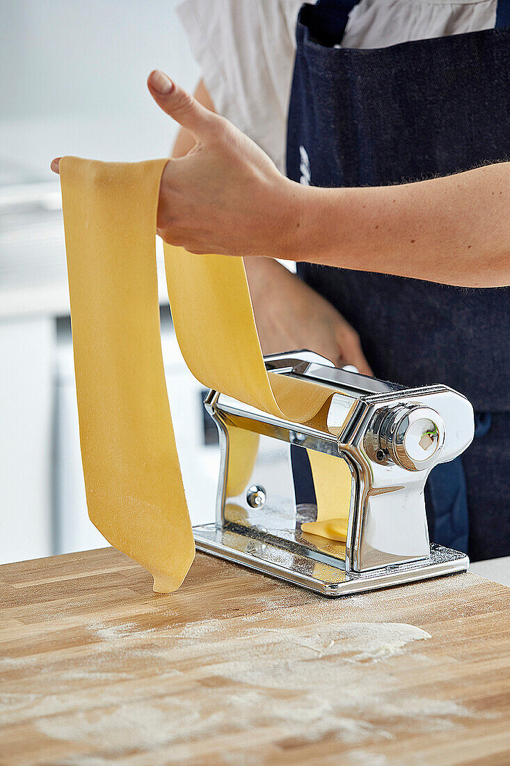 Pasta being made: a pasta sheet being put through a pasta machine