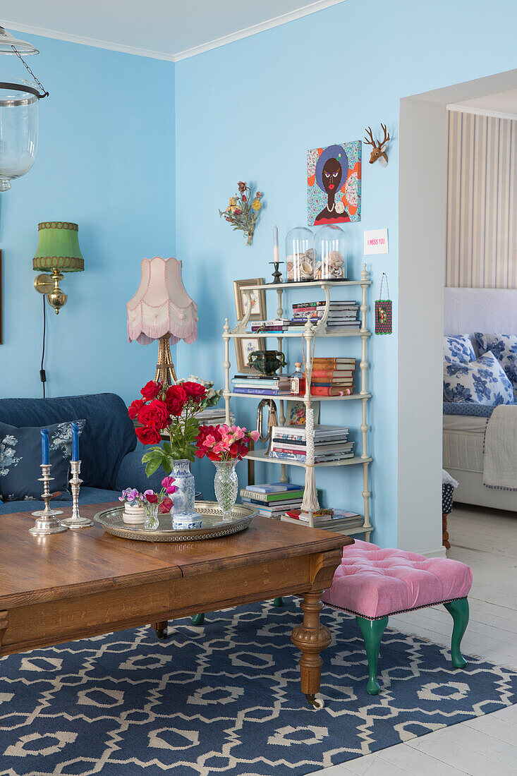 Coffee table with flowers and white shelf in the living room with light blue walls