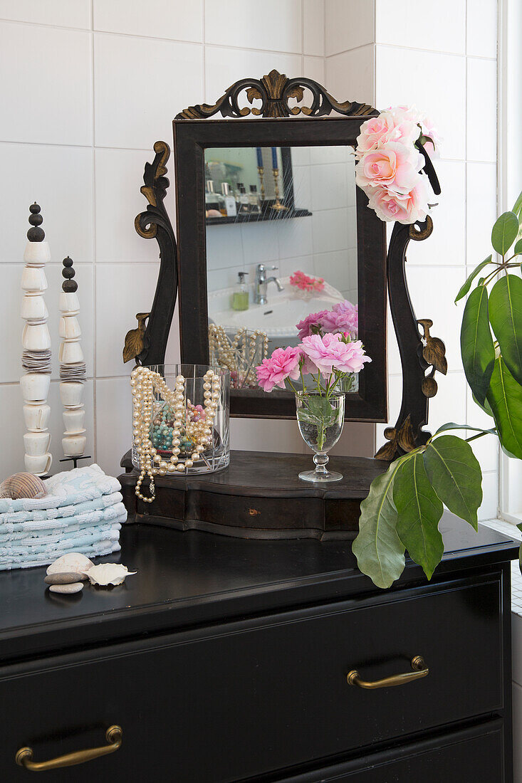 Antique vanity mirror with flowers and lady's accessory on black dresser