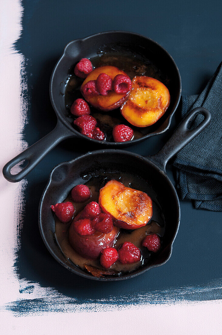 Drizzled peaches with raspberries in cast iron pans