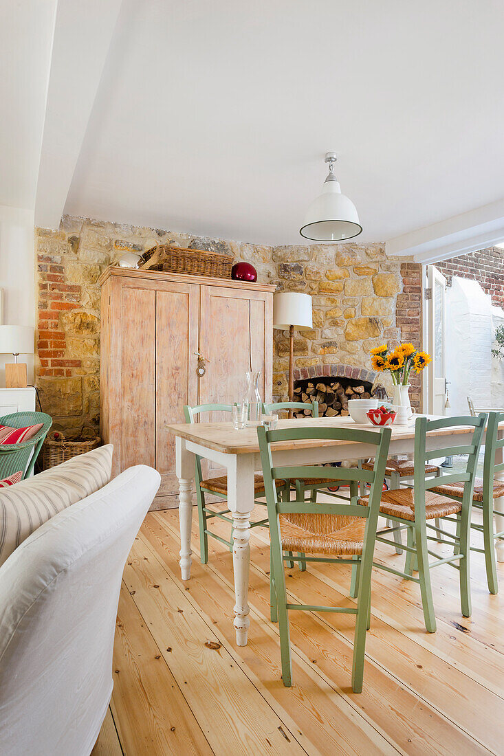 Dining area with Mediterranean flair, in the background wooden cupboard and exposed sandstone wall