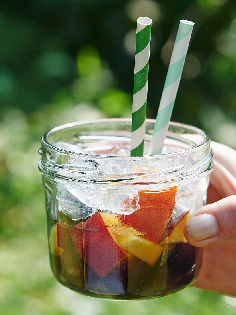 Fruit cocktail in a jar with ice and straws
