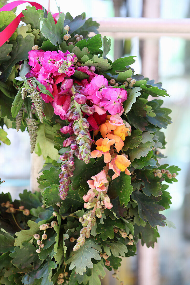 Oak leaf wreath with colorful flowers of snapdragons and Stocks