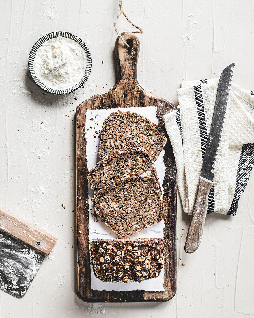 Seeded bread on a board with utensils