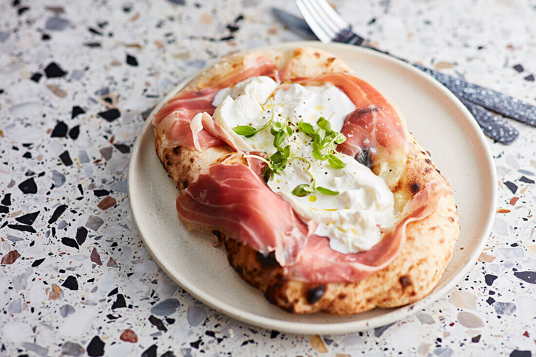 Parmaschinken und Burrata auf gebackenem Brot