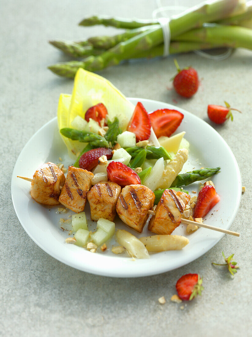 Chicken kebab served with a spring salad with asparagus, strawberries and melon