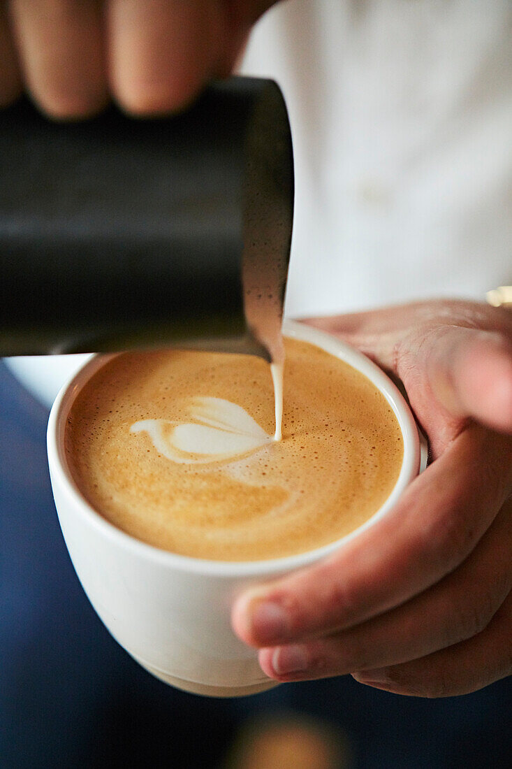 Barista pours milk foam with latte art