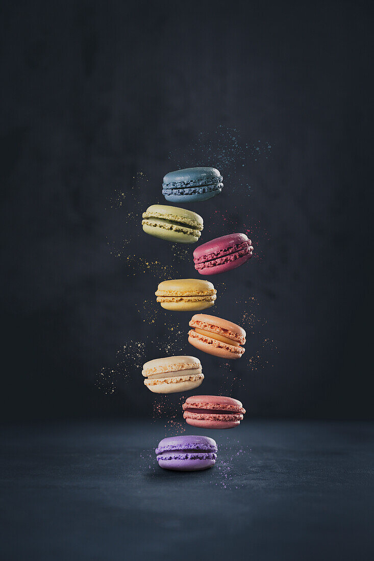 Bunte schwebende Macarons vor dunklem Hintergrund