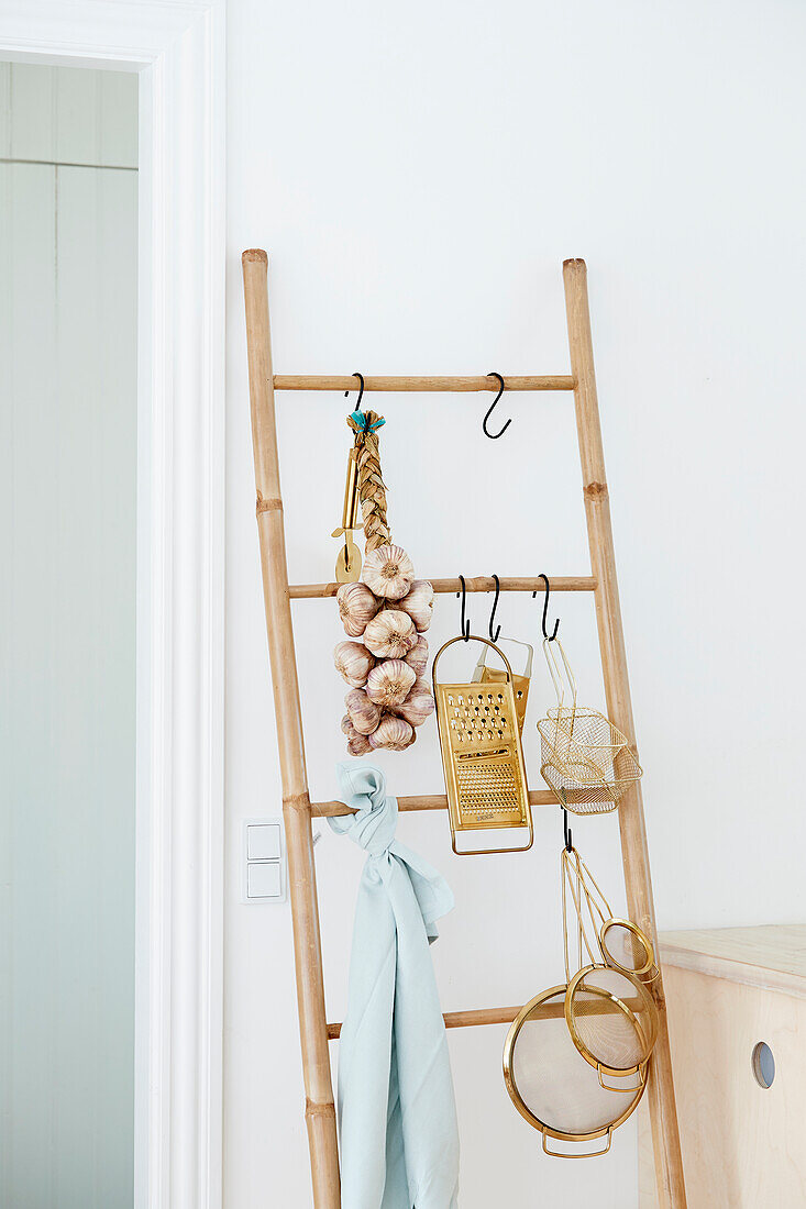 Garlic braid and kitchen utensils hanging from bamboo ladder