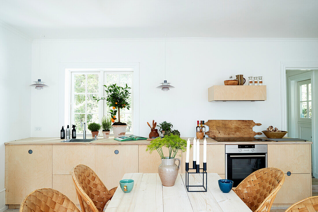 Dining table with wickerwork chairs in front of kitchen unit