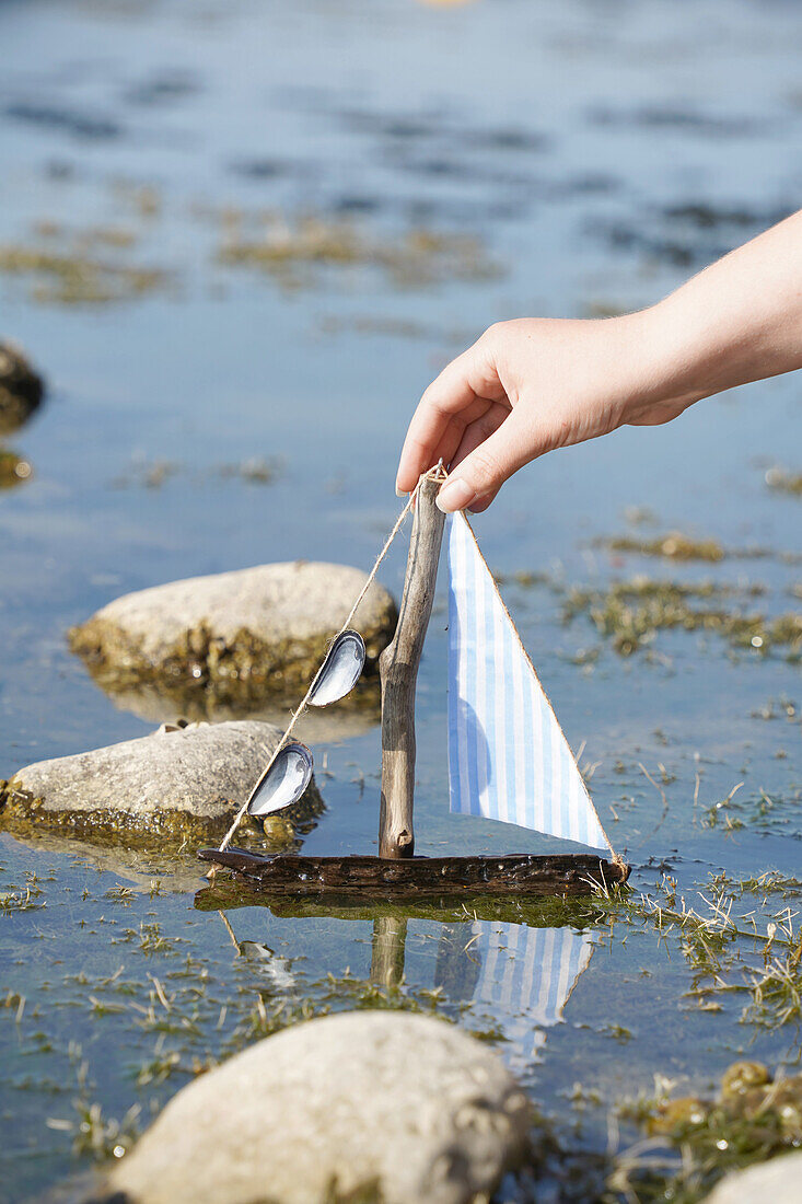 Handgefertigtes Segelboot aus Treibholz und Stoff im Wasser