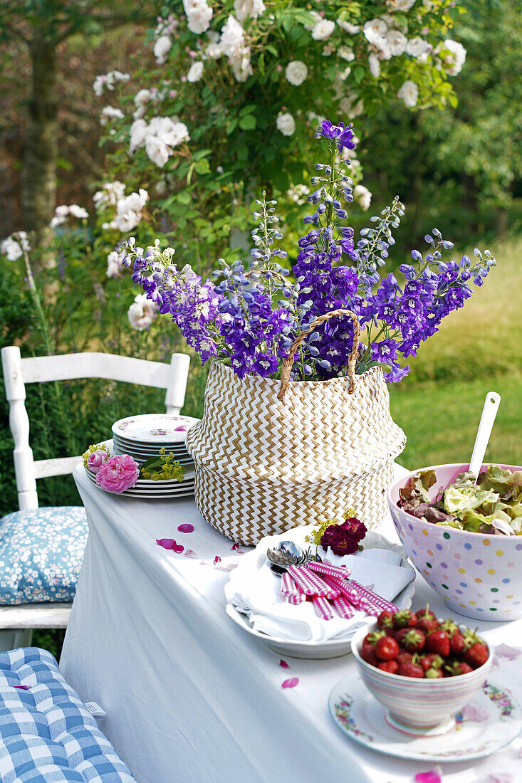 Summer table setting with strawberries, salad and delphinium