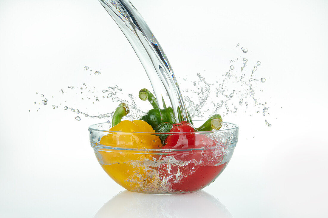 Water pouring into bowl of peppers