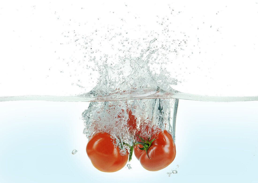 Three tomatoes splashing in water