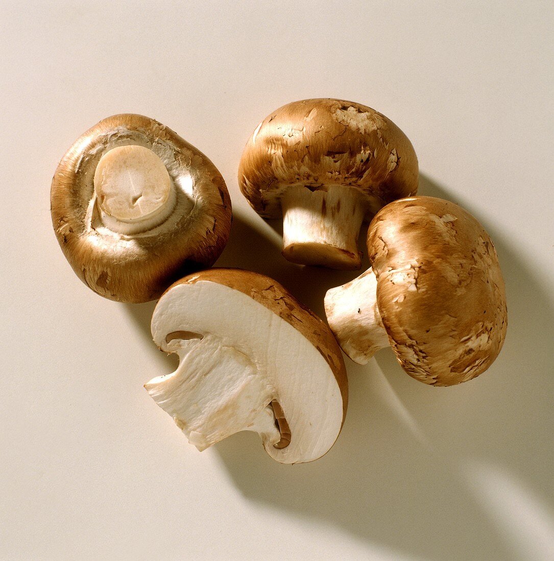 Three whole and one half brown mushrooms