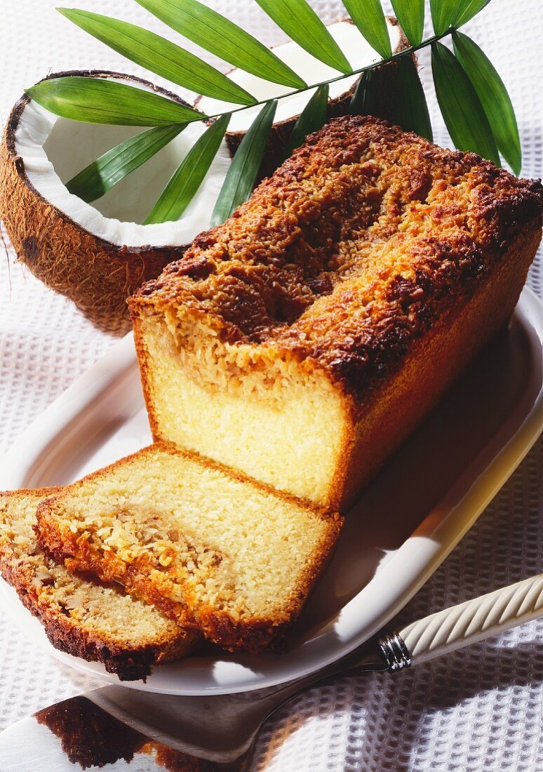 Kokosnußkuchen in Kastenform, angeschnitten auf Kuchenplatte