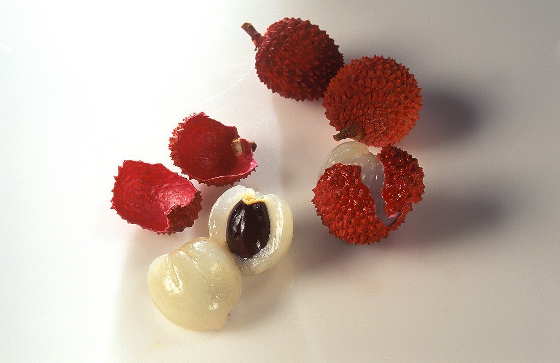 Two whole lychees, one opened  and one halved