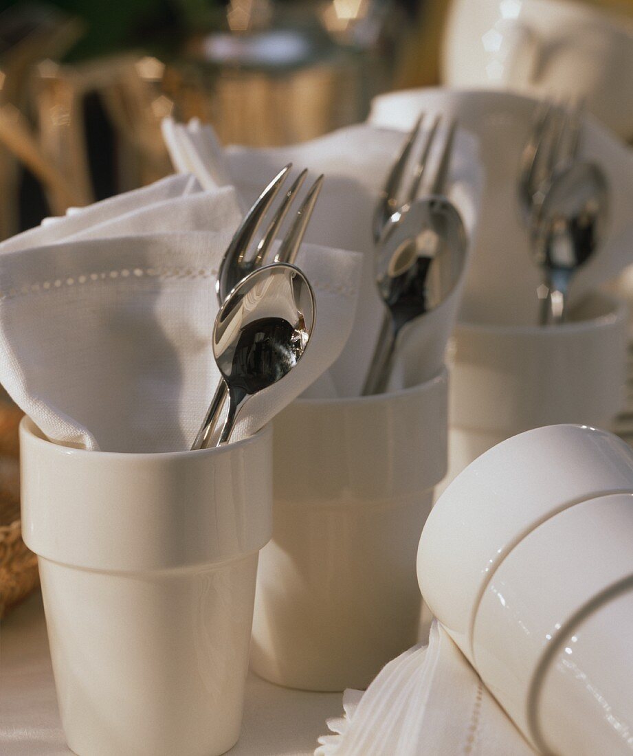 Cutlery and napkins in ceramic mugs (table decoration)