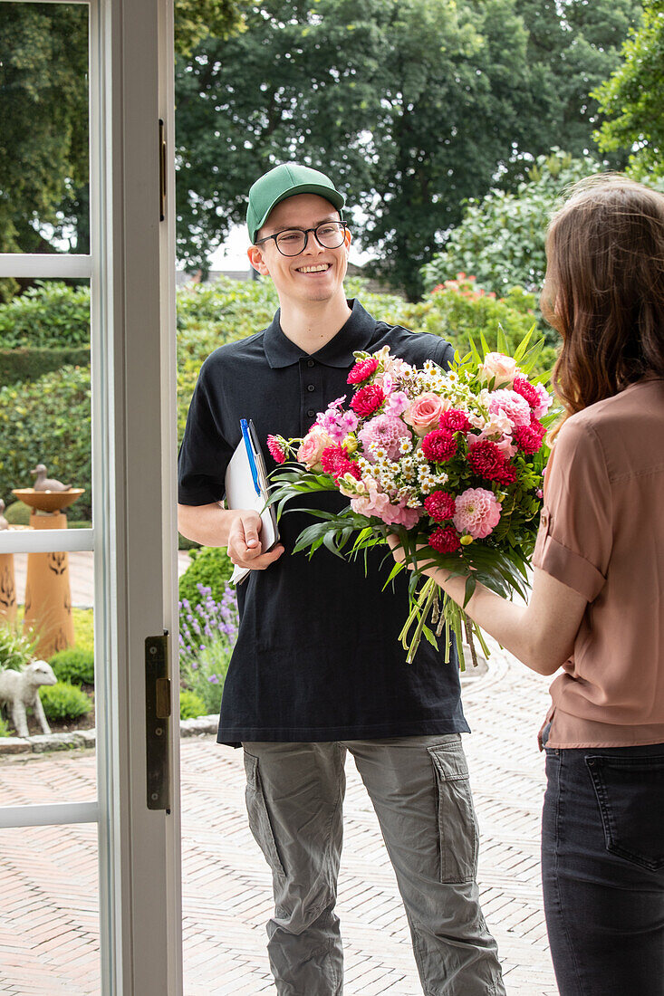 Delivery service - supplier hands over bouquet of flowers