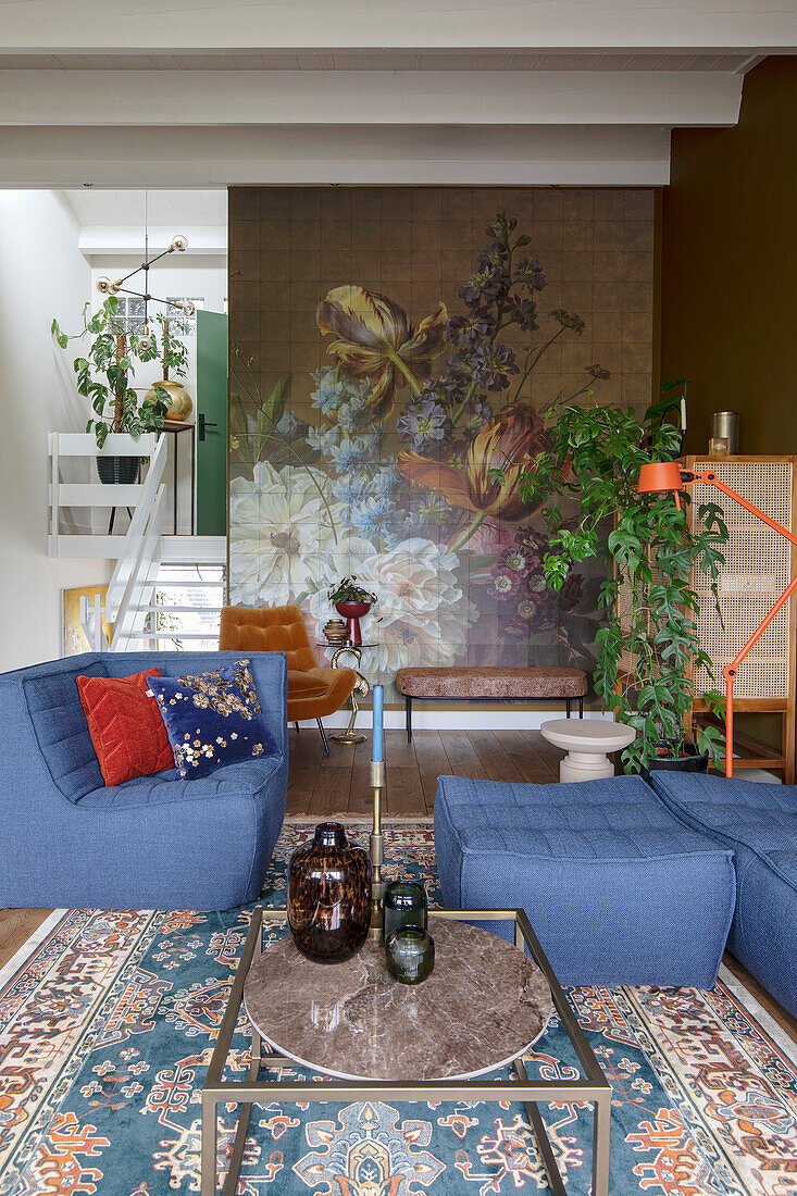 Living room with floral wallpaper, blue armchairs and oriental carpet