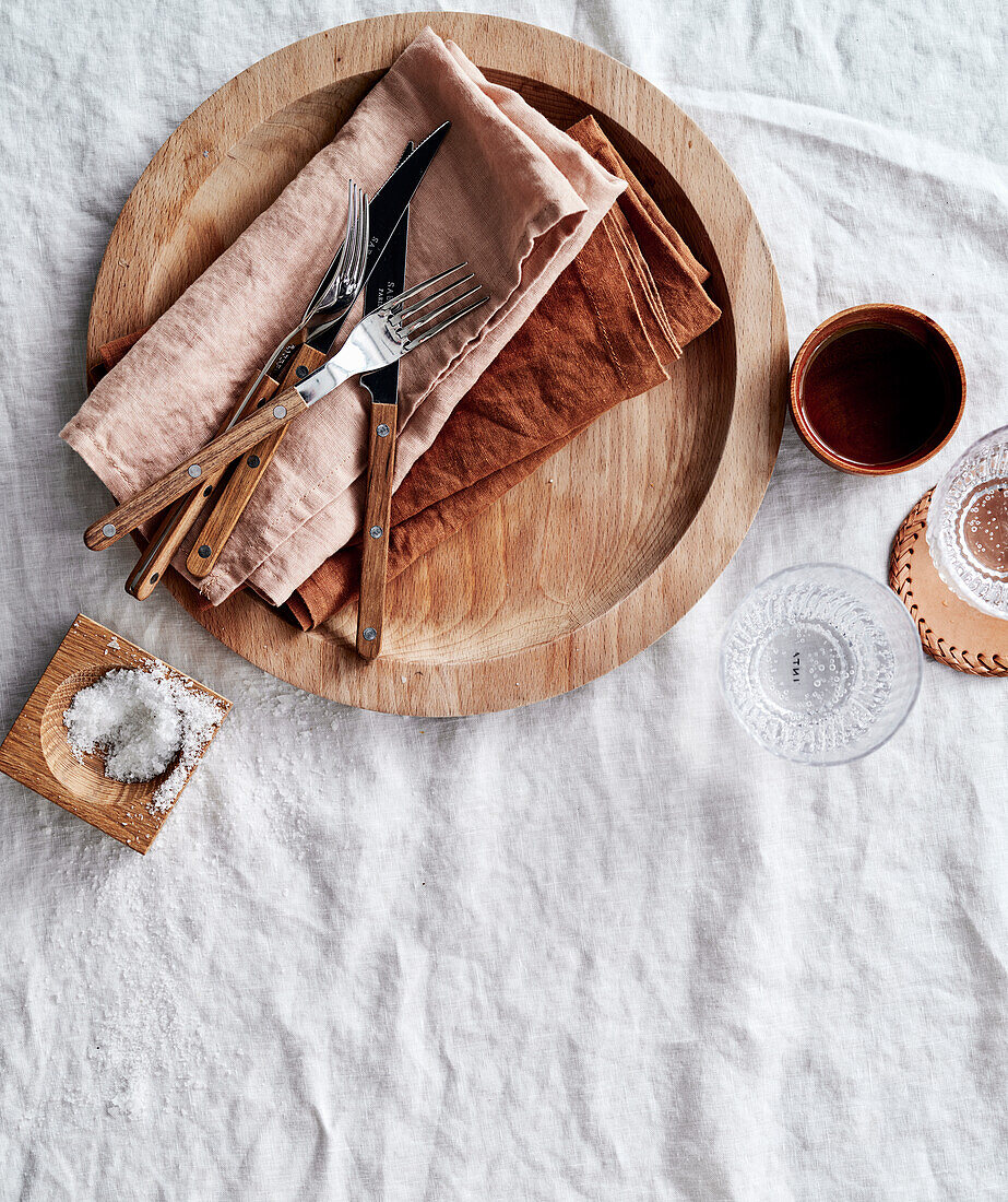 Cutlery and napkins on a wooden plate