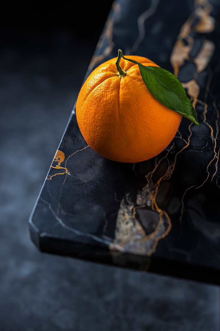 Orange mit Blatt auf schwarzem Marmor