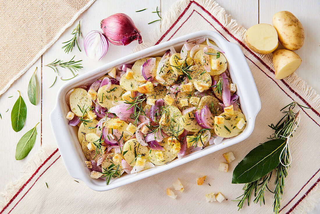 Baked potatoes with bread cubes, herbs and red onions