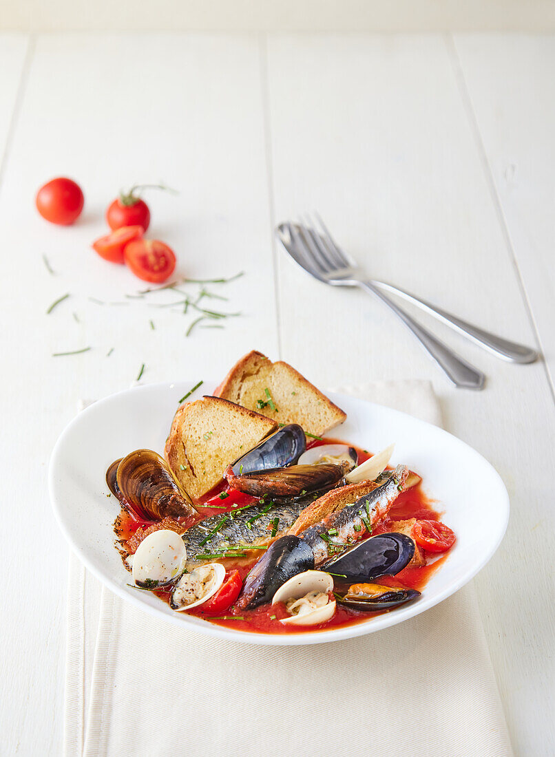 Tomatensuppe mit Fisch, Muscheln und geröstetem Brot