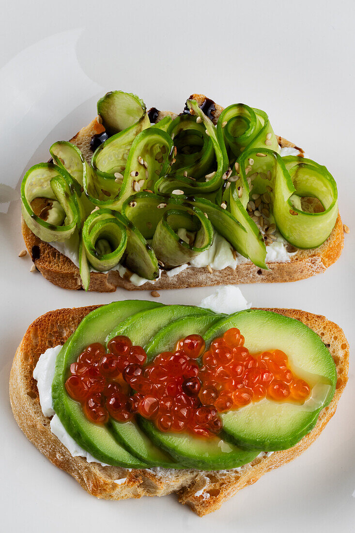 Two sandwiches with cream cheese, cucumber, avocado and caviar