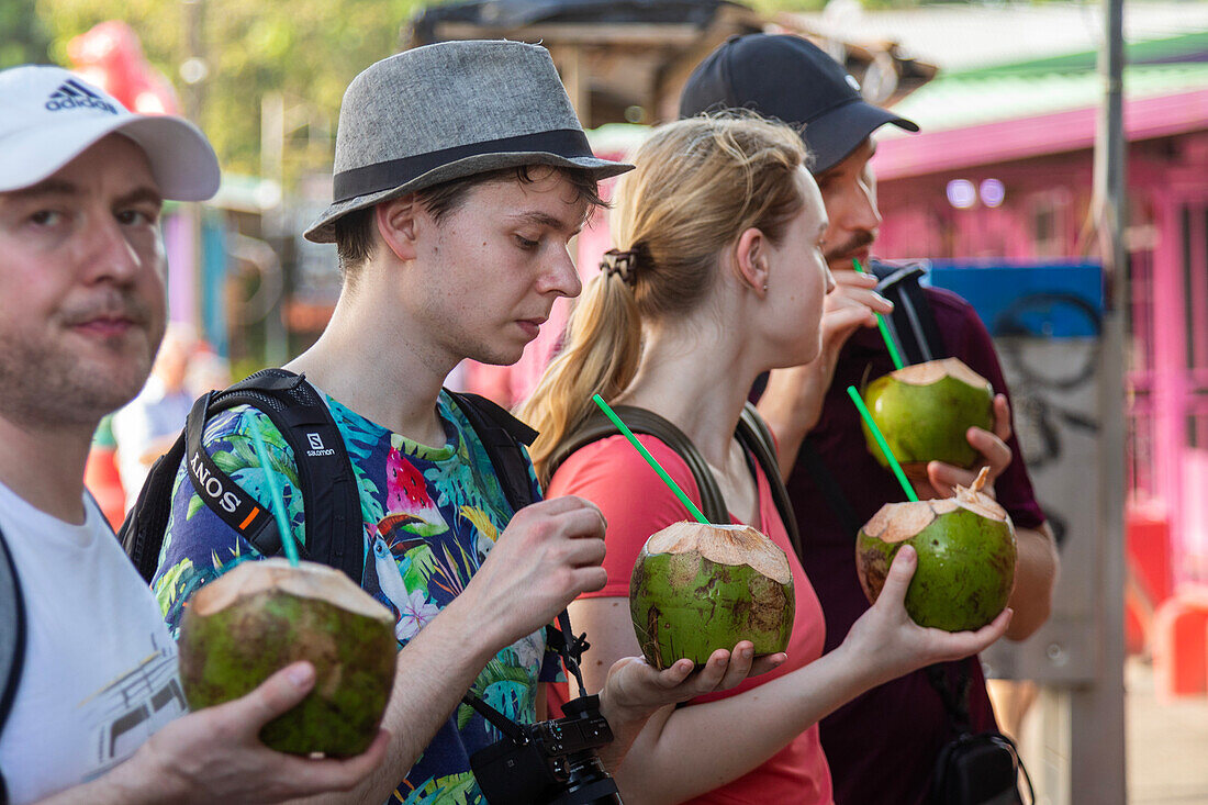 Tourists drinking from coconuts