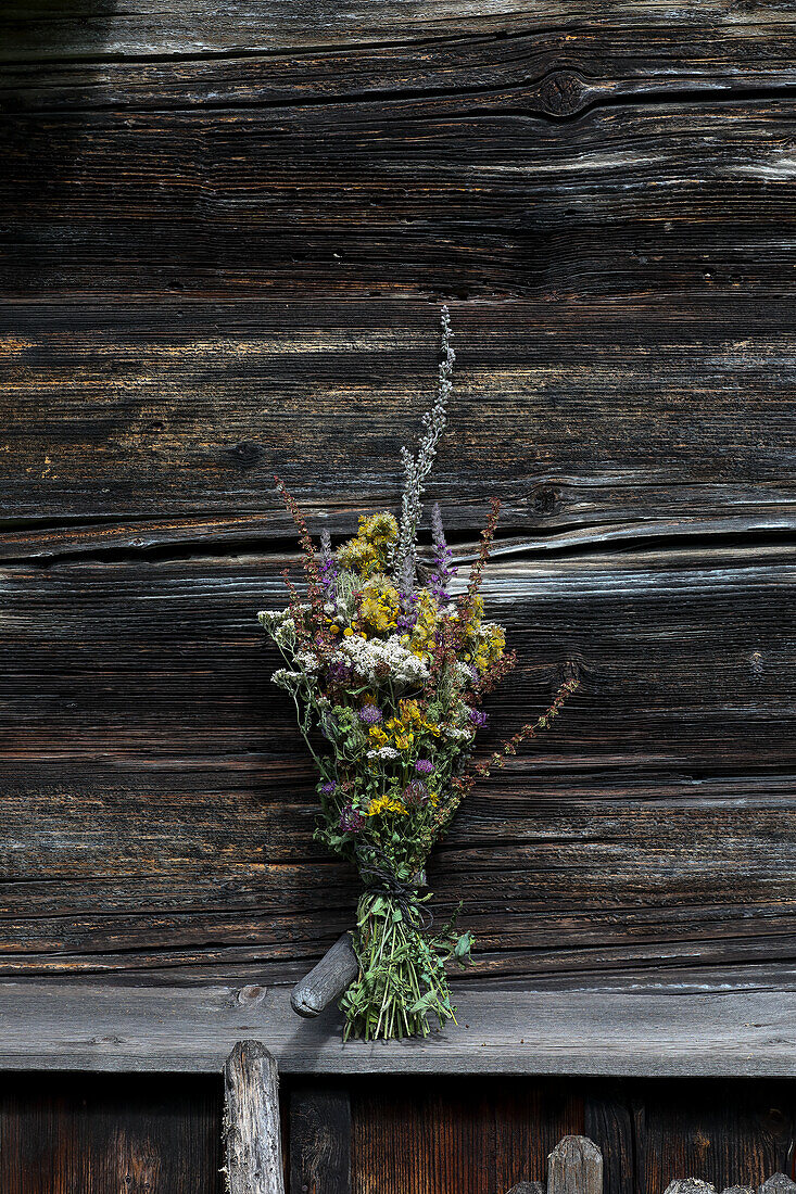 Bouquet of flowering herbs in front of a weathered wooden wall