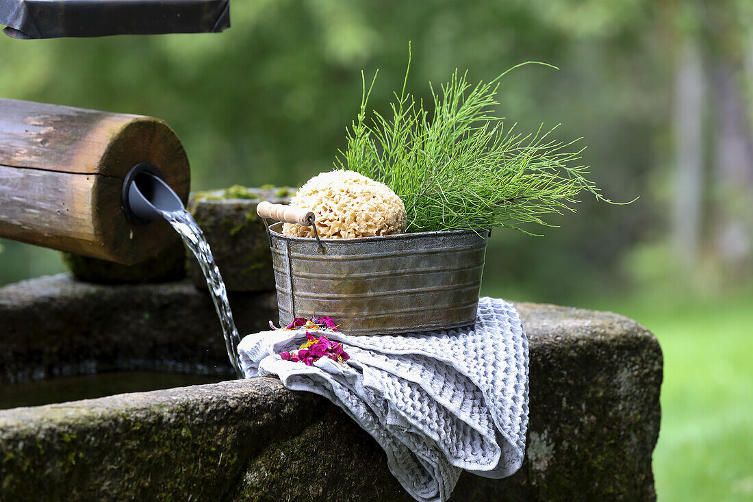 Bowl with sponge, horsetail and towel by a fountain