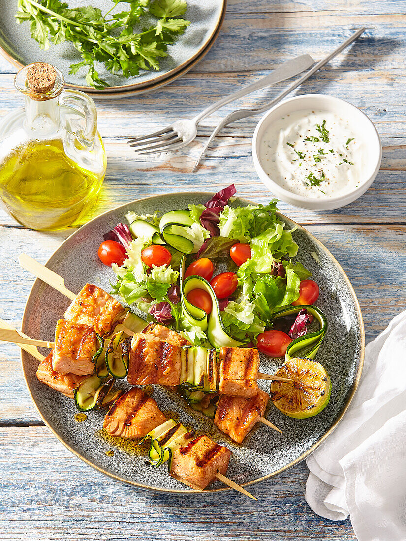 Grilled salmon skewers with mixed salad and yoghurt dip