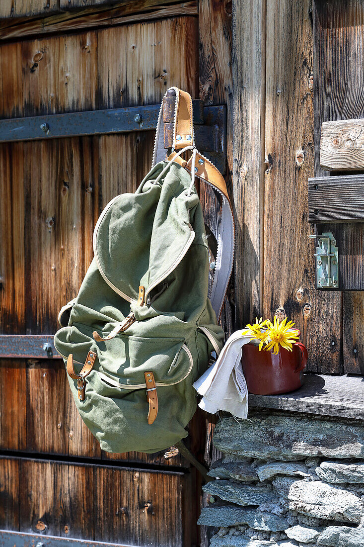 Wanderrucksack, Emailletasse und Arnikablüten