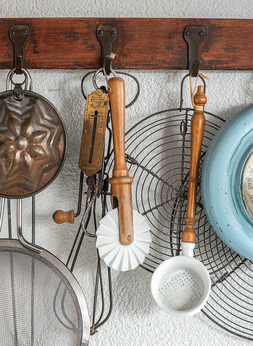 Vintage kitchen utensils hanging on wooden hook rail