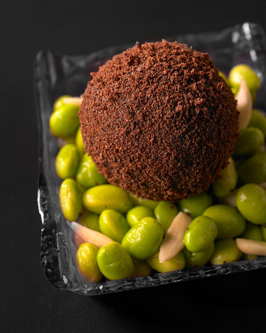 Foie gras in a black truffle coating on broad beans