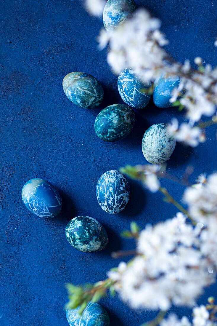 Blaue Ostereier auf blauem Hintergrund mit blühenden Kirschblüten