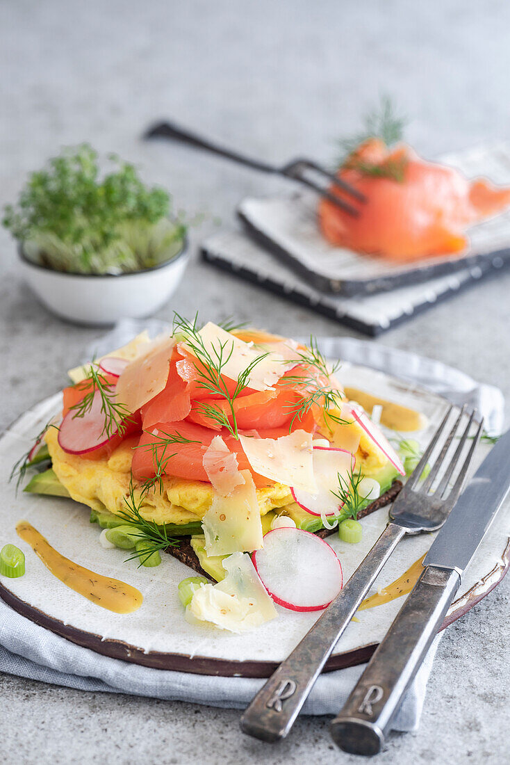 Belegtes Brot mit Avocado, Rührei, Räucherlachs und Käsespänen