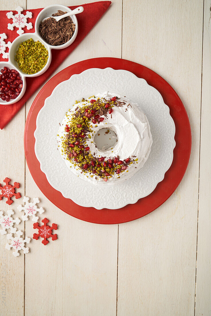 Donut cake with white icing and pistachio, pomegranate and chocolate