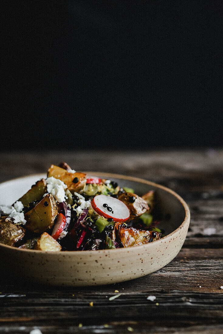 Roast potato salad with black lentils, radishes, onions and goat's cheese