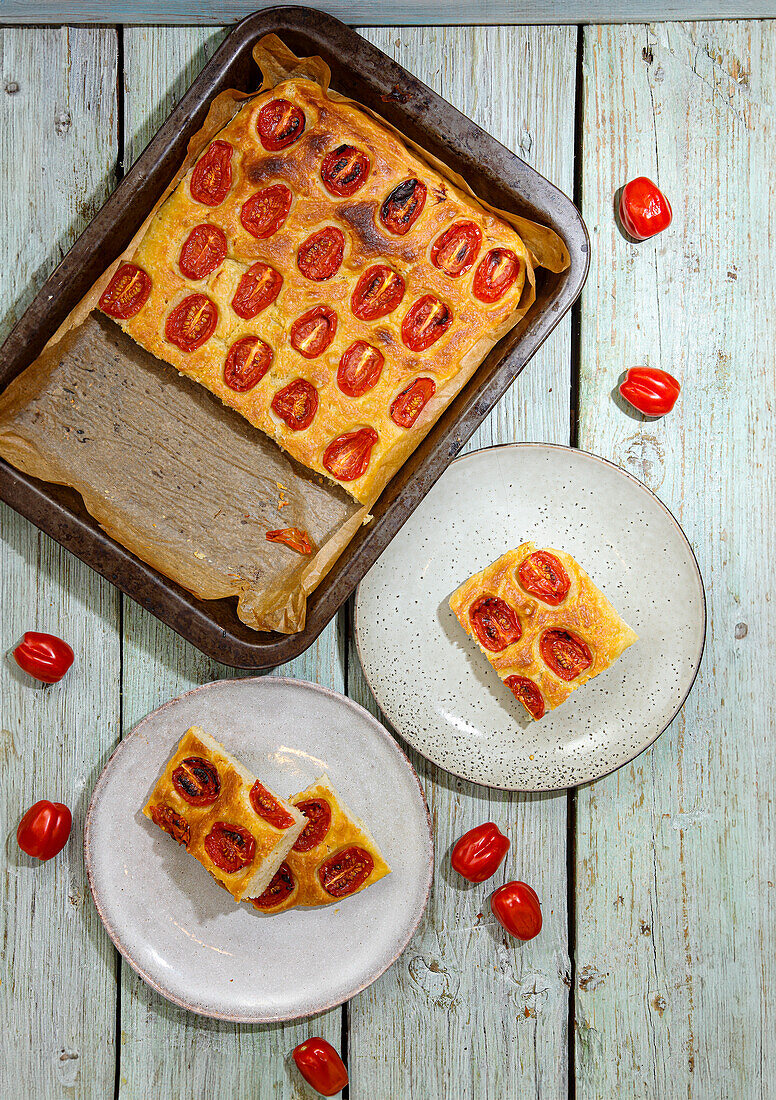 Tomaten-Focaccia auf Blech und Stücke auf Tellern