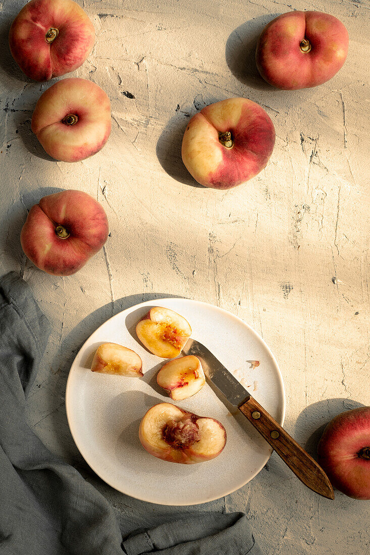 Whole flat peaches and a piece of fruit on a plate