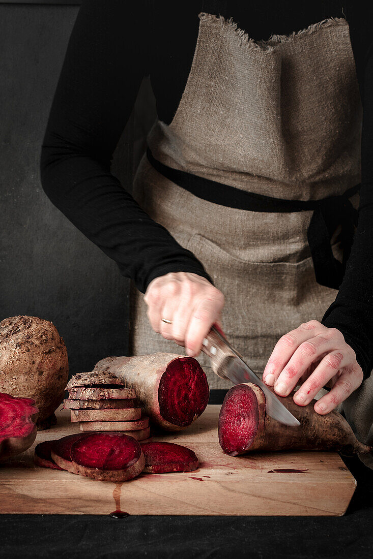 Woman slicing raw beetroot on a wooden board
