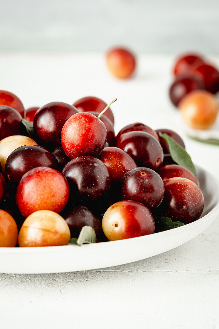 Red mirabelle plums in a white bowl