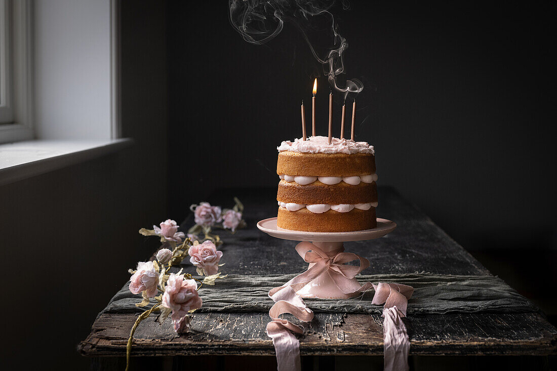 Vanilla naked cake with pink icing and candles