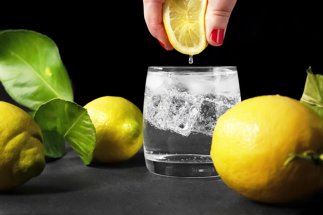 Zitronensaft in ein Glas Wasser pressen