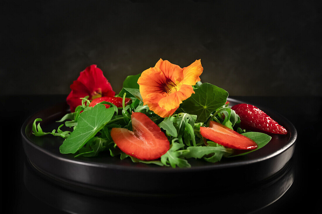 Rocket salad with strawberries, nasturtium leaves and nasturtium flowers.