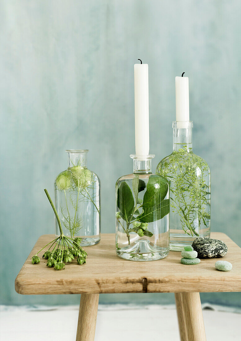 Decorative candle holders made from glass bottles filled with plants