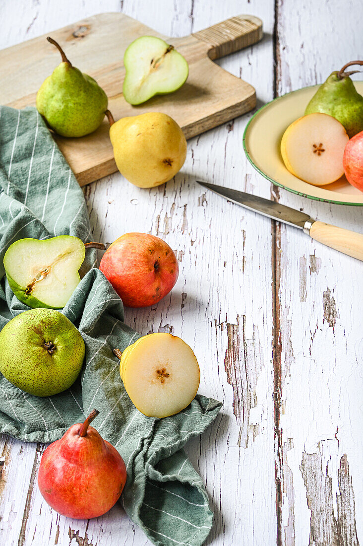 Mixed pears on a chopping board, white wooden background